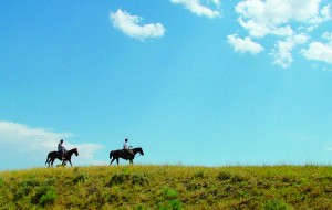 Two horsemen riding a ridge in Montana on the other kind of horsepower.