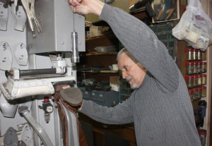 This pneumatic shoe press is the key to bonding new soles for a proper shoe repair. Note the variety of cast steel shoe lasts hanging on the left. There are many more out of view.